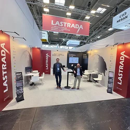 Messestand Lastrada Bauma warmes Grau mit großen Rot-Weißen Logo und zwei Personen